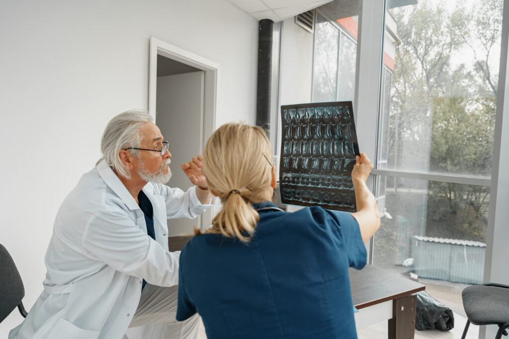 A team of doctors examine spinal x-rays of a patient with back pain.