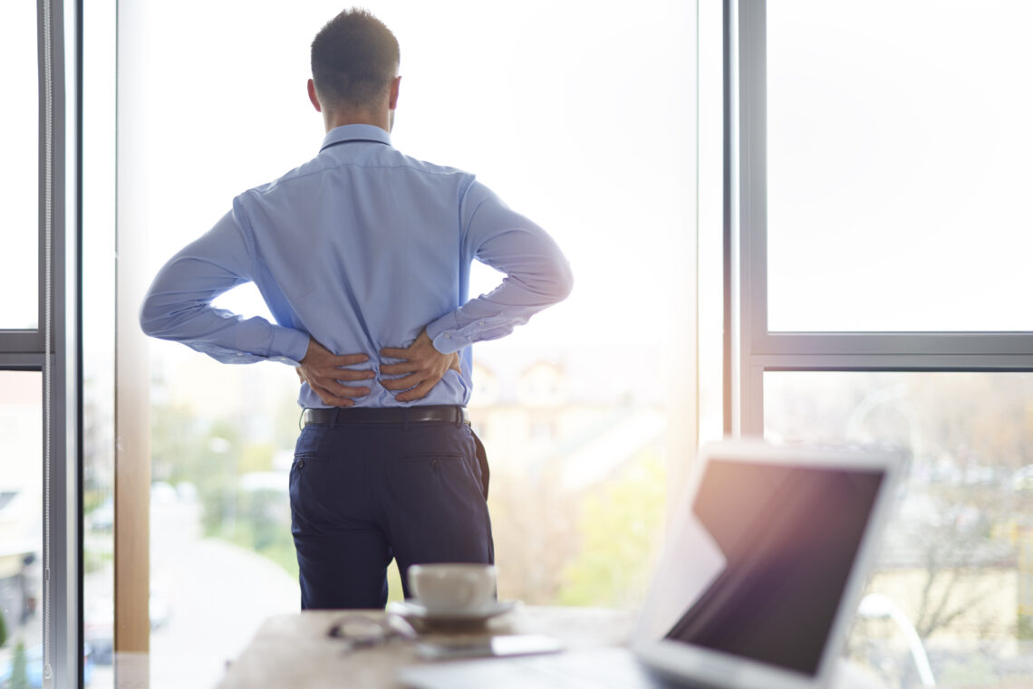 Business man in office suffering from back pain.